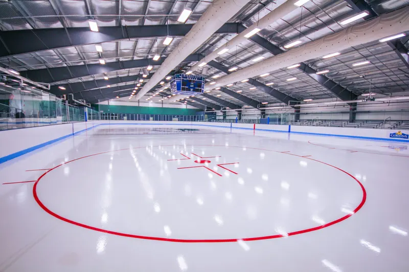 Red face-off circle on a bright indoor ice sheet under arena lights