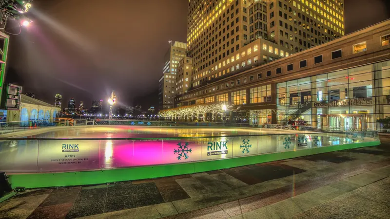 Outdoor ice rink lit at night with skyscrapers behind it